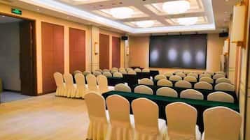A conference room with rows of chairs, a long table, and a projection screen.