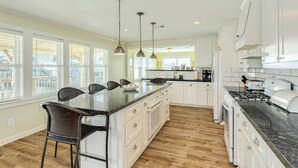 Une cuisine spacieuse dotée d’un grand îlot central, de meubles blancs et d’un plancher en bois.