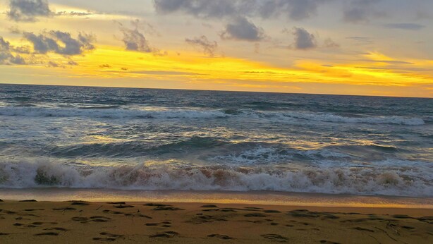 Une plage avec des vagues et un coucher de soleil.
