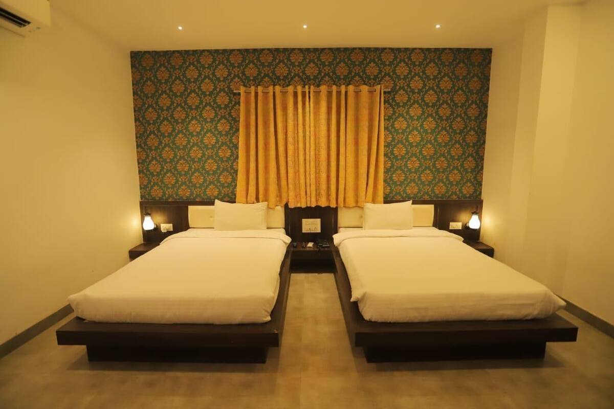 A double room with two beds, a patterned wall, and a curtain.
