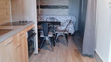 Une cuisine compacte avec des meubles en bois, un four encastré et un coin repas comprenant une table et des chaises.