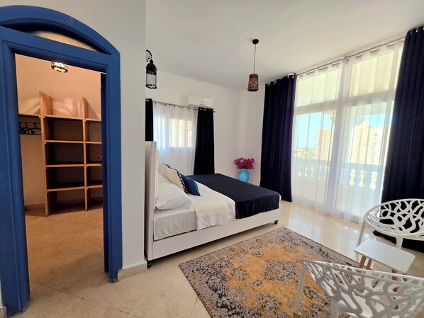 Een slaapkamer met een bed, een kledingkast, een bureau en een stoel.