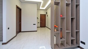 Un pasillo con una puerta de madera, una pared blanca y una repisa con un jarrón y flores.