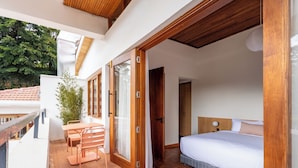 A bedroom with a large bed, a wooden ceiling, and a balcony with a table and chairs. - Céline & Lolo (Nairobi)
