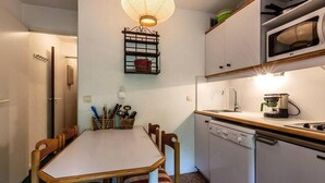 Cocina compacta con mesa, sillas, microondas, cafetera y lavavajillas.