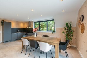 Een moderne keuken met een eethoek, houten kastjes en een groot raam.