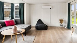 A modern living room with a grey sofa, black bean bag, and a small round table with a vase. - 5 Star Holiday Home in Slagelse (Slagelse)