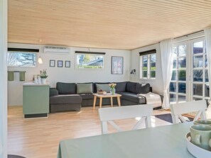 A modern living room with a sofa, a dining table, and a kitchen area with a window.