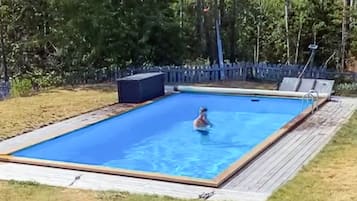 A rectangular swimming pool with a wooden deck surrounding it.