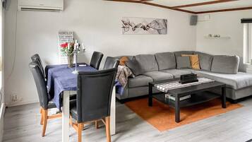 A modern living room with a gray sofa, a dining table with chairs, and a coffee table.