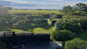 A garden with a lawn, various plants, a pergola, and a pathway.