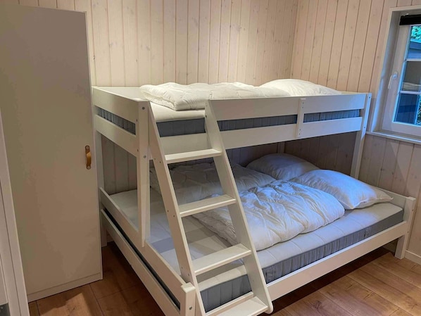 Un lit superposĂ© avec une Ă©chelle, des murs en bois et une fenĂȘtre.