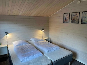Une chambre avec deux lits, des murs en bois et des lampes fixées au mur.