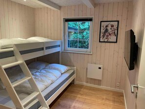 A bunk bed room with a window, a framed picture, and a wall-mounted TV.
