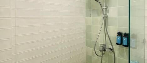 A shower with a handheld showerhead, a glass-enclosed shower area, and a small shelf with toiletries.