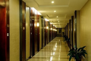 A hotel corridor with doors on both sides, a shiny floor, and potted plants. - Northwest A&F University Foreign Expert Apartment (Xianyang)