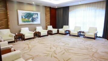 A hotel room with a large carpet, a painting on the wall, and a large window with curtains.