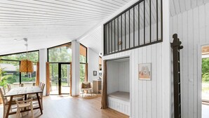 A spacious living area with a dining table, chairs, a sofa, and a fireplace. - 5 Star Holiday Home in Hasle (Nykobing Sjaelland)