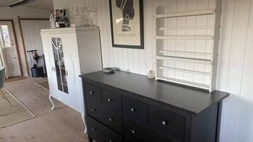 Una habitación con un aparador negro, un armario blanco y un cuadro en la pared.