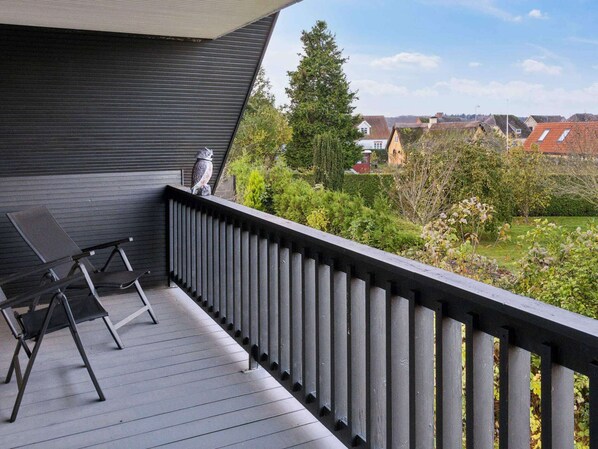 A balcony with a dark railing, a chair, and a statue. - 5 Star Holiday Home in Bandholm (Bandholm)