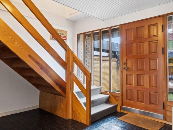Eine Holztreppe führt zu einer Tür mit Glasschildern.