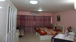 Un dormitorio con cama, cortinas, una mesita de noche y un aire acondicionado instalado en la pared.