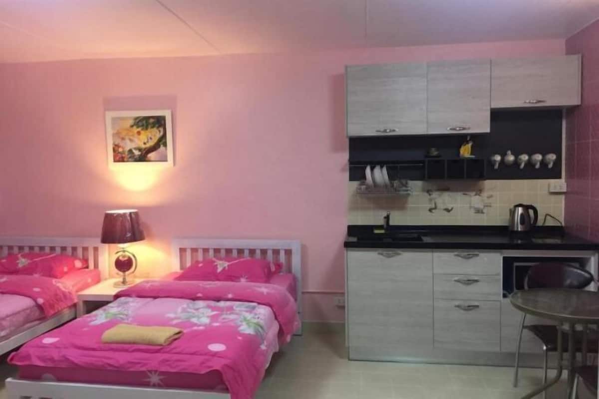 Een slaapkamer met twee bedden, een kleine kitchenette en een eethoek.
