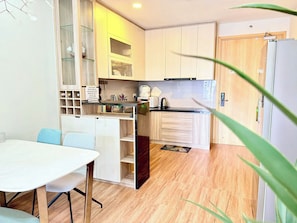Une cuisine compacte avec des meubles en bois, un plan de travail blanc et un coin repas comprenant une table et des chaises.