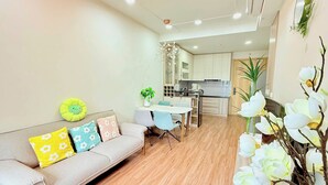 Una sala de estar moderna con sofá, una mesa de comedor y una cocina al fondo.