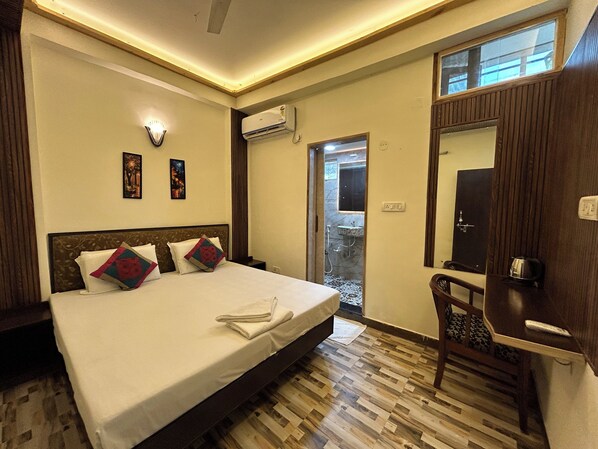 A hotel room with a bed, bedside table, nightstand, and a mirror.