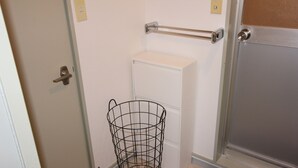 Une salle de bain avec un lavabo blanc, un porte-serviettes et un panier en fil de fer noir.