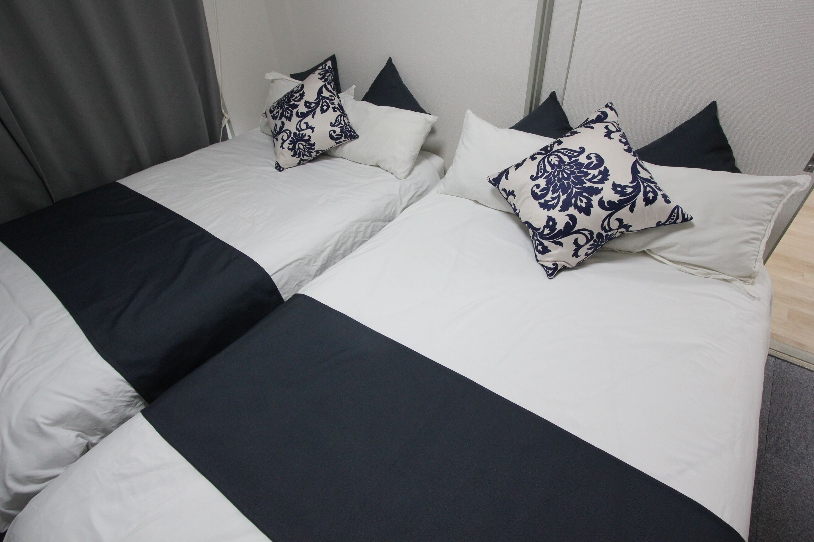 Een tweepersoonsbed met een zwart-wit sprei en decoratieve kussens.