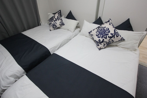 Uma cama de casal com colcha preta e branca e almofadas decorativas.