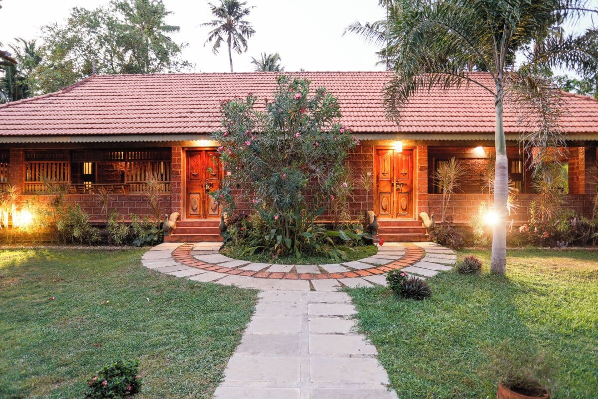 A brick house with a tiled roof, a central garden, and a stone pathway leading to the entrance.