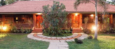 A brick house with a tiled roof, a central garden, and a stone pathway leading to the entrance.