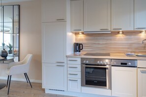 Una cocina moderna con armarios blancos, un horno empotrado y una cafetera en la encimera.