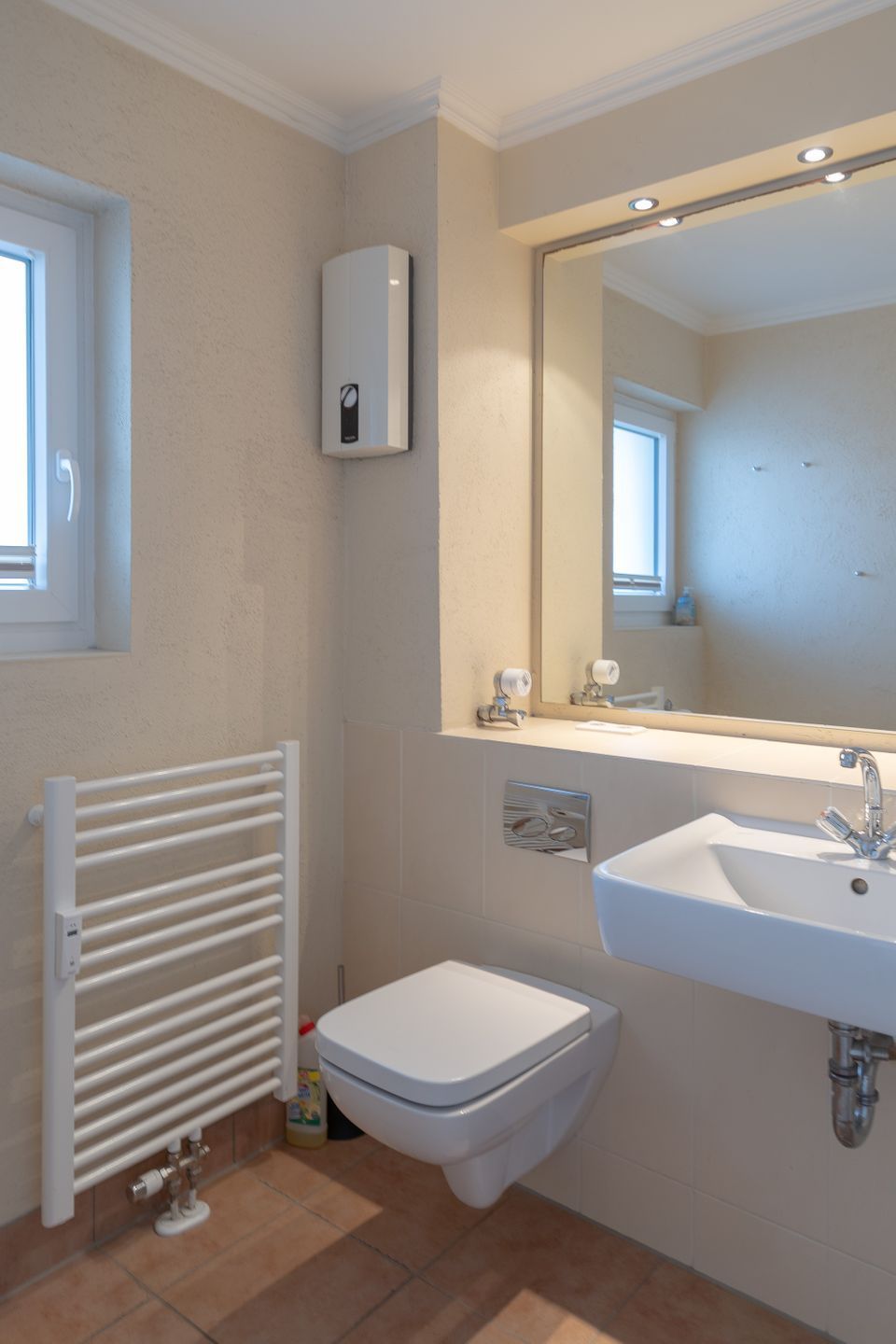 Ein Badezimmer mit Waschbecken, Toilette, Heizkörper und Spiegel.