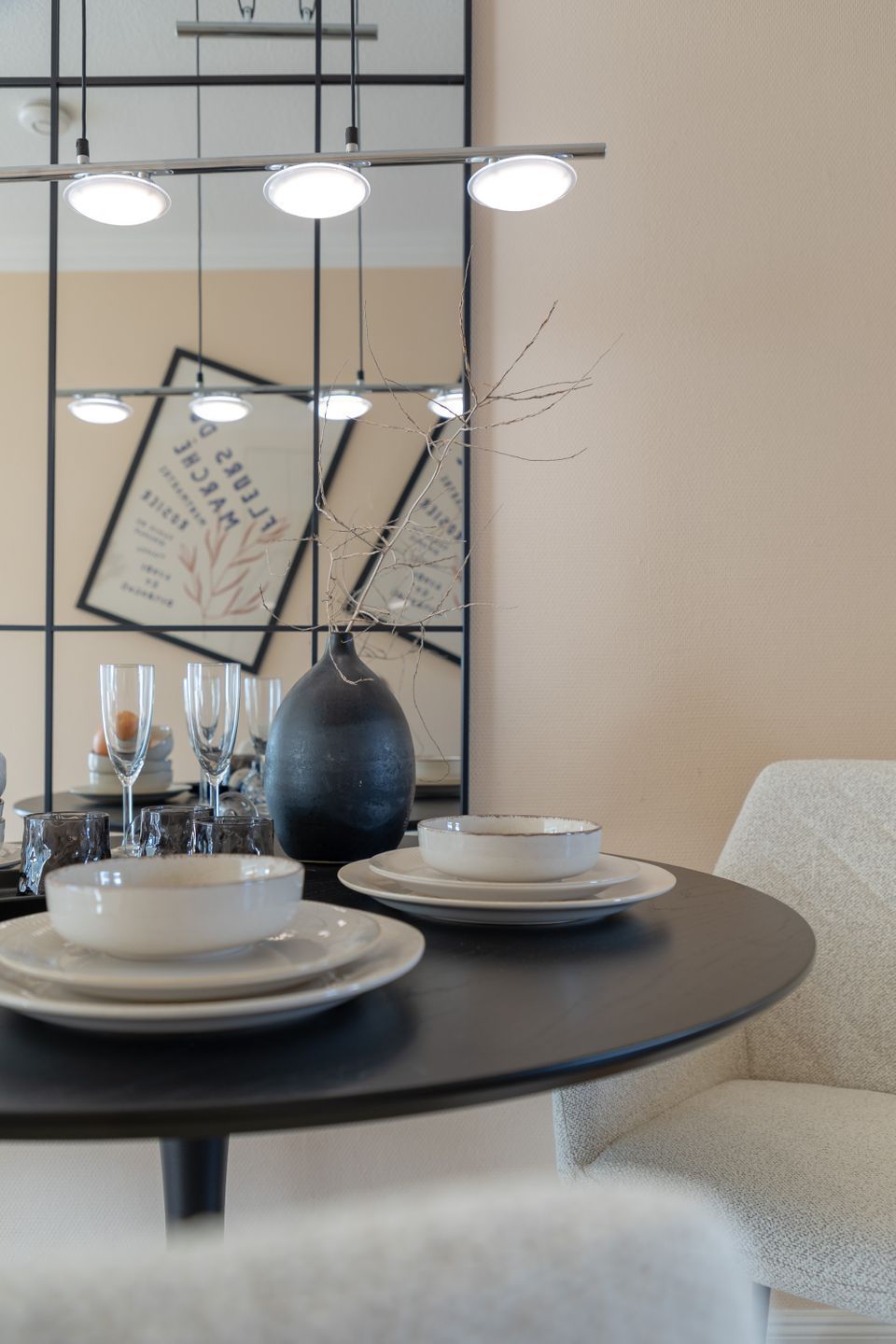 A dining area with a round table, plates, glasses, and a vase.