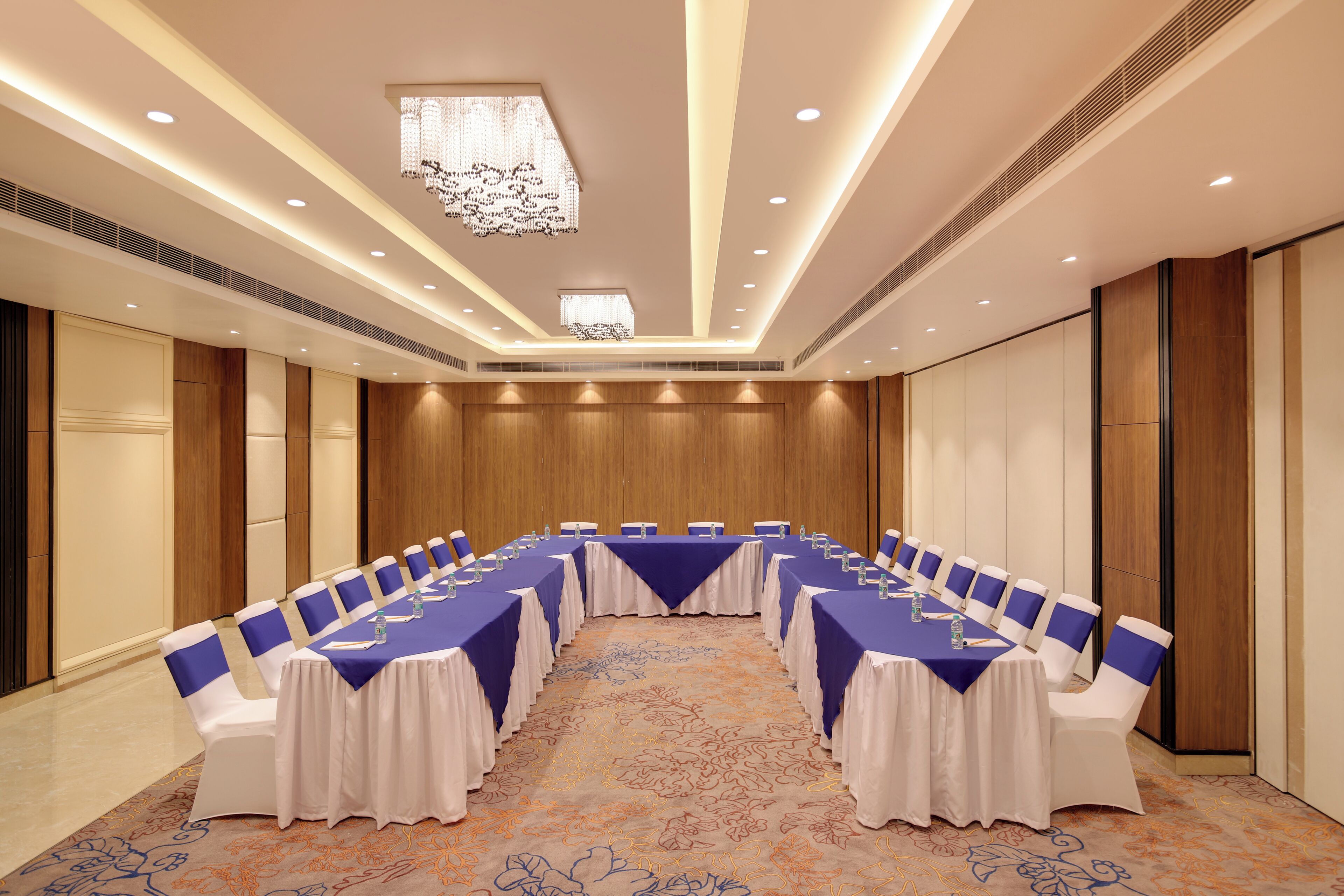 A conference room with a long table, white chairs, and blue sashes.