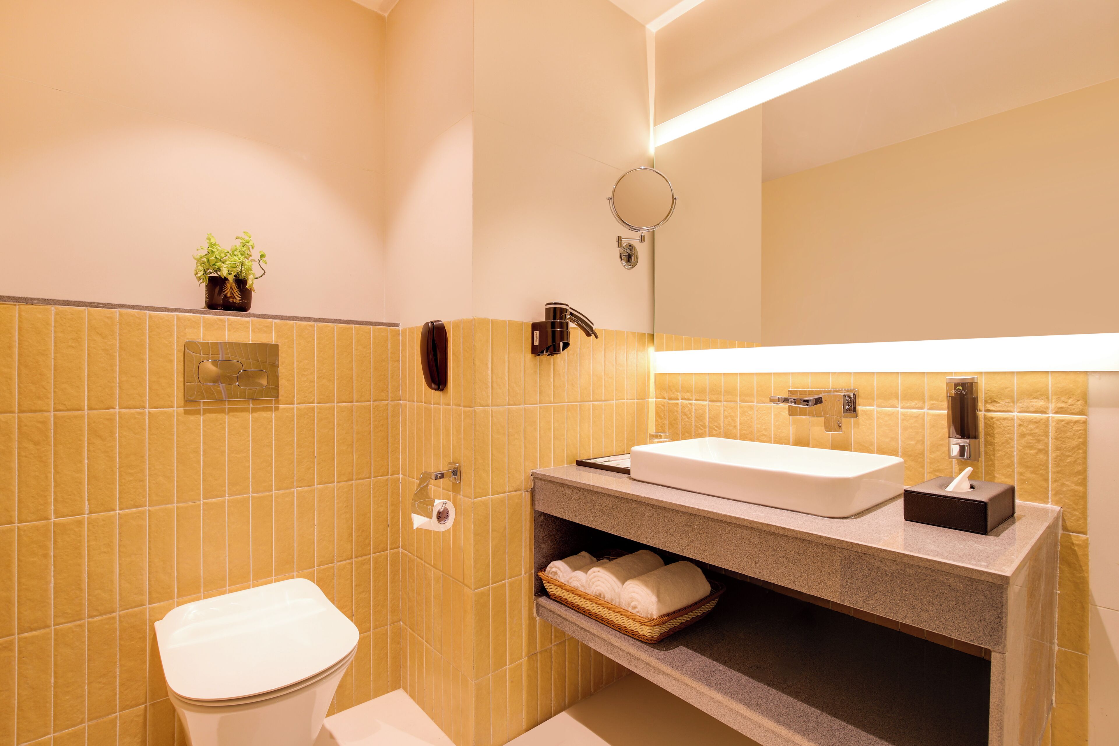 Ein Badezimmer mit Toilette, Waschbecken mit Spiegel darüber und Ablage für Handtücher.