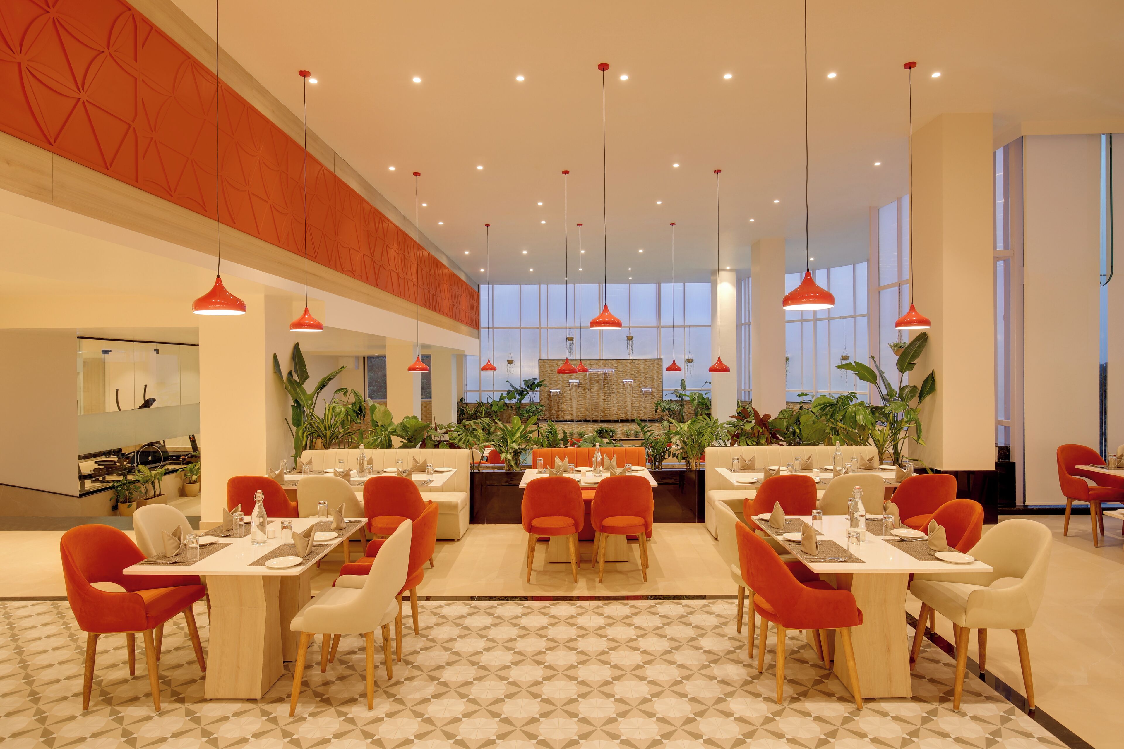 A spacious dining area with multiple tables and chairs, a central kitchen area, and large windows allowing natural light.