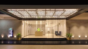 Una moderna area di reception con un divisorio in vetro, una scrivania e piante in vaso.