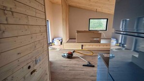 A room with wooden walls, a large window, a refrigerator, and a vacuum cleaner on the floor. - 5 Star Holiday Home in Ronde (Ronde)