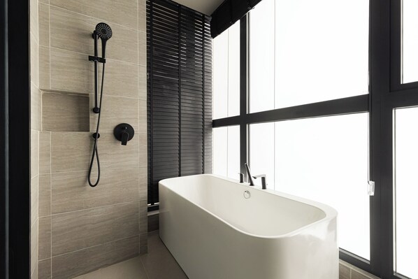 A modern bathroom with a freestanding bathtub, a showerhead, and a window providing natural light. - NaiBnB in Antara Genting (Genting Highlands)