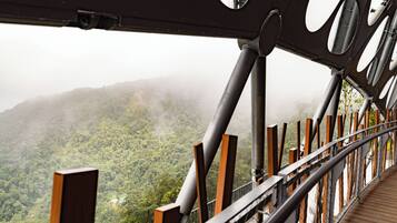 A wooden observation deck with metal railings overlooking a forested mountain range.