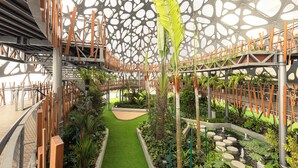 An indoor garden with a central pathway, surrounded by greenery and a unique ceiling design. - NaiBnB in Antara Genting (Genting Highlands)