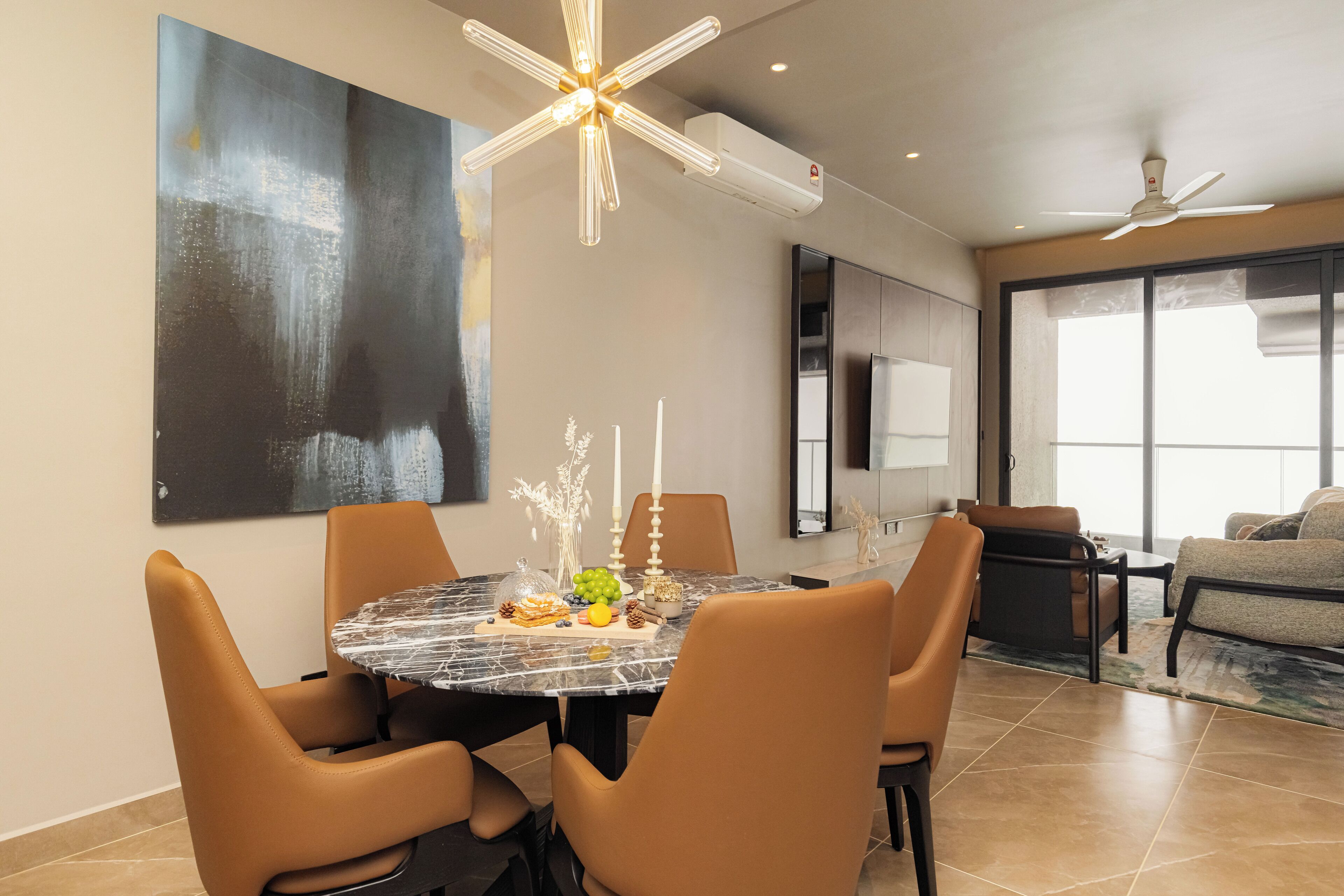 A modern dining area with a round marble table, leather chairs, and a contemporary ceiling light fixture.