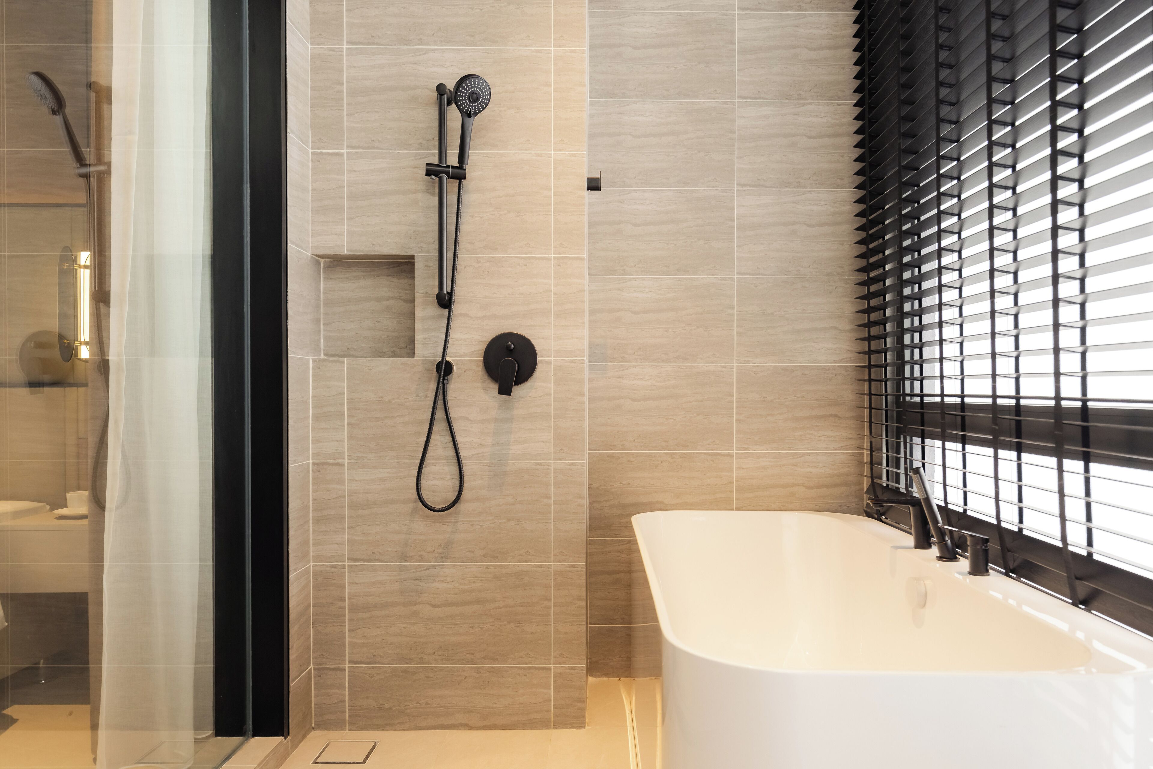Une salle de bain moderne avec une baignoire sur pieds, une douche avec un pommeau de douche amovible et un espace de douche délimité par des parois en verre.