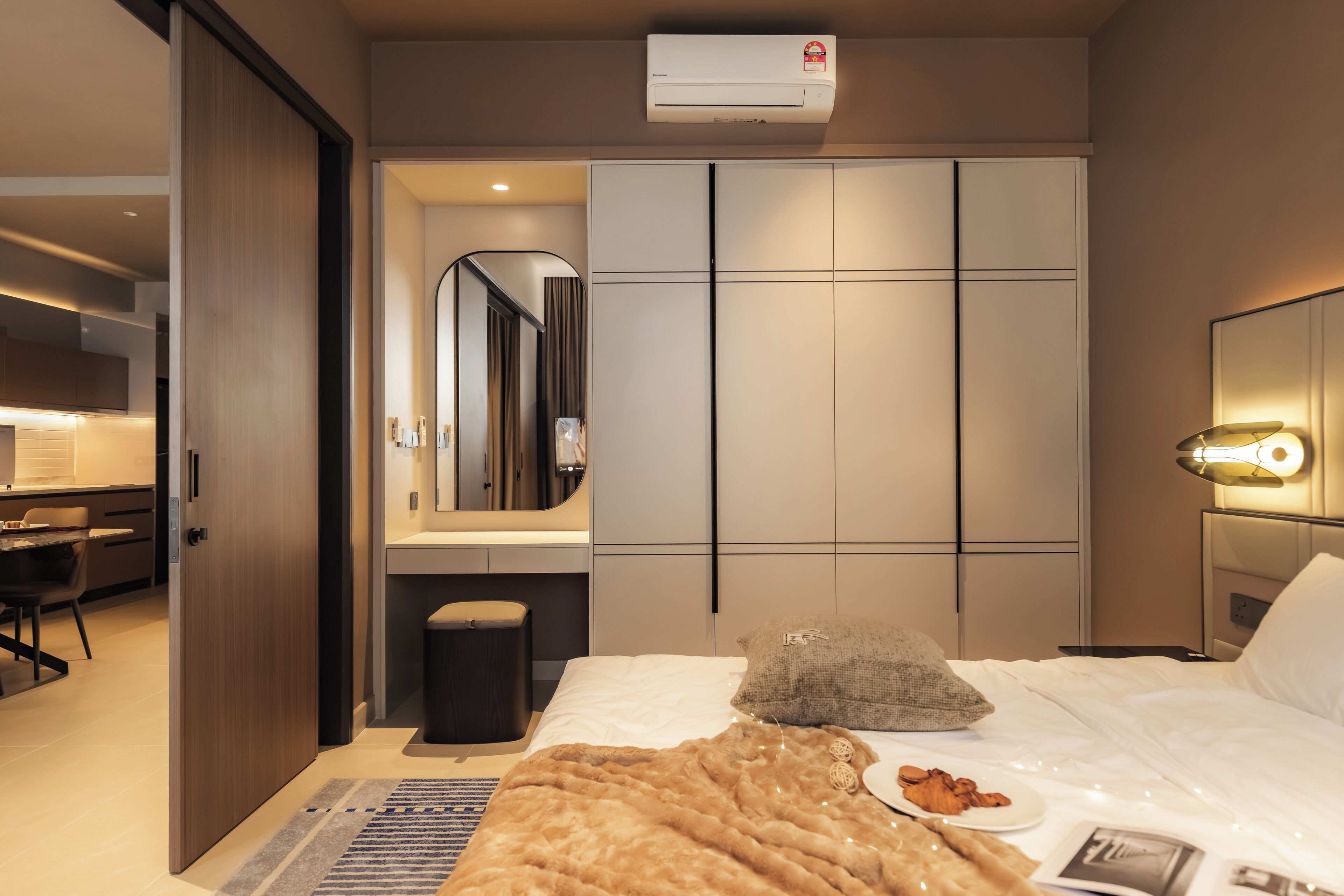 A modern hotel room with a bed, bedside table, and a large mirror.