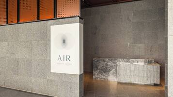 A reception area with a sign reading "AIR Resort Suites," a marble bench, and a textured wall.